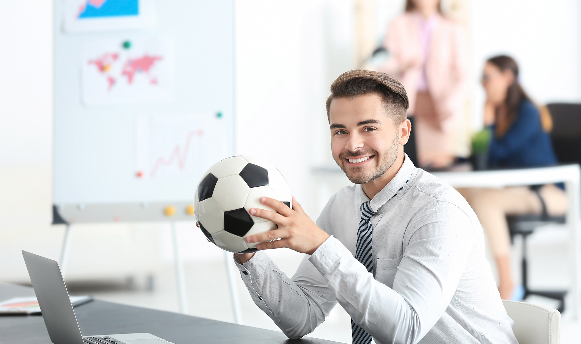 Man at desk holding a soccer ball